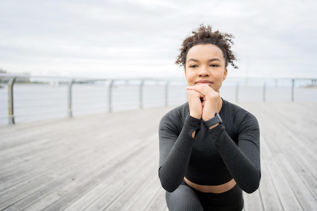 Een vrouw in een strak trainingspak en traint buiten Een fitnesshorloge en een hardloop-app zijn bij de hand