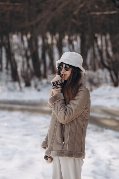 een vrouw in een winterpark eet een bitterkoekje