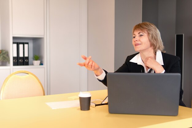 Een vrouw in een wit overhemd coacht luisteraars in de bedrijfsruimte