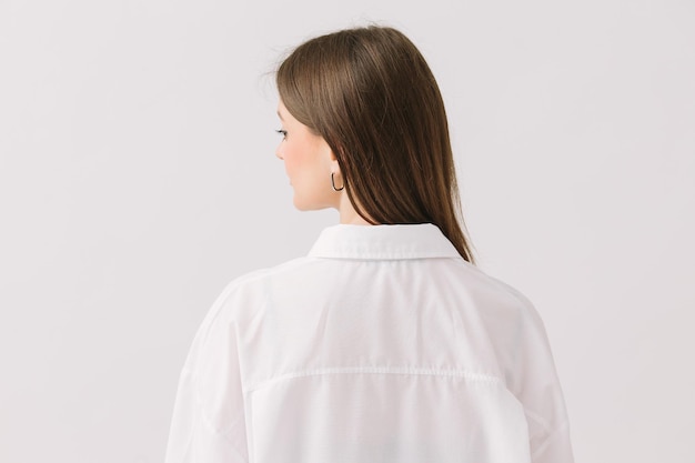 Een vrouw in een wit overhemd staat tegen een witte achtergrond