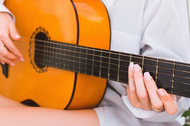 Foto een vrouw in een wit shirt speelt de gitaar close-up