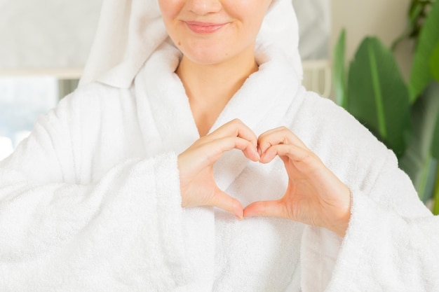 een vrouw in een witte jas toont met haar vingers een hartsymbool, een hartgebaar