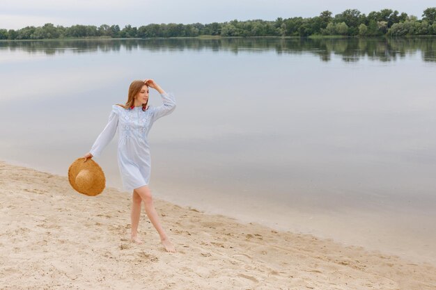 Een vrouw in een zomerjurk met een strohoed die danst in de zomer