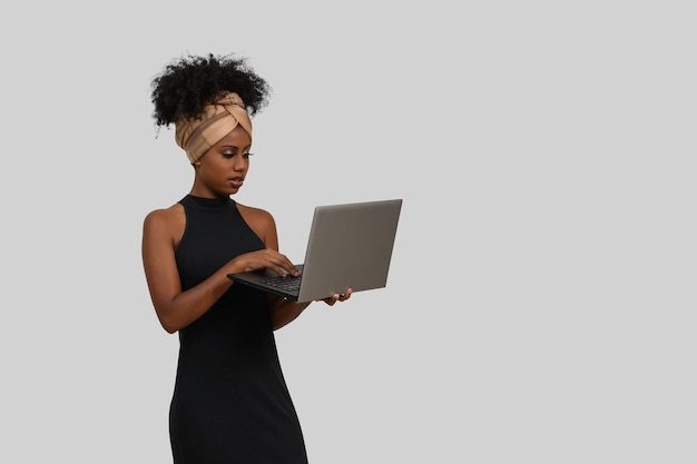 Een vrouw in een zwarte jurk gebruikt een laptop.