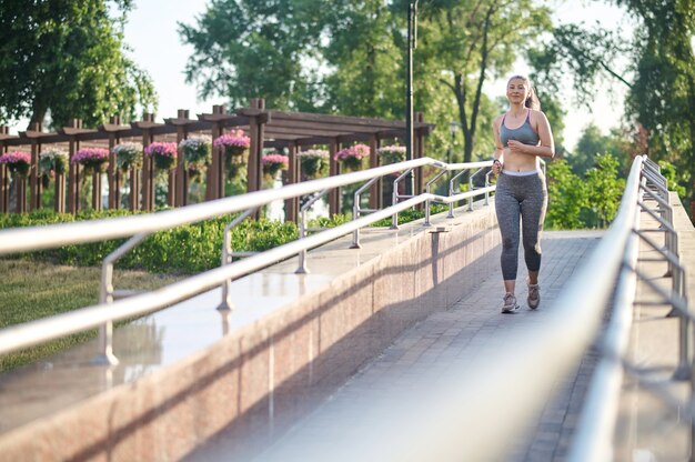 Een vrouw in grijze sportkleding die jogt in het park