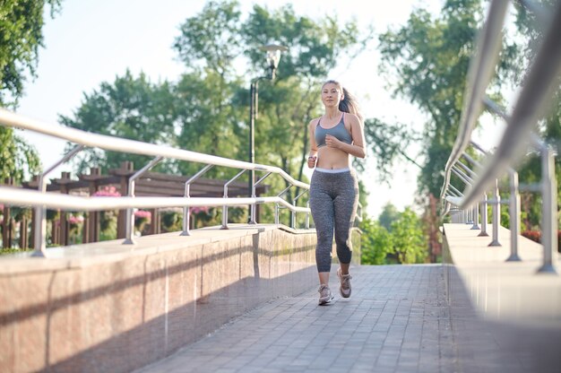 Een vrouw in grijze sportkleding die jogt in het park