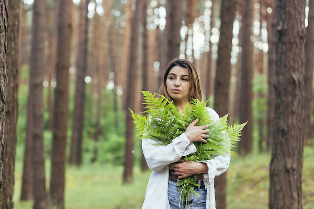 Een vrouw in het bos knuffelt een boeket varens, een jonge activist beschermt het bos