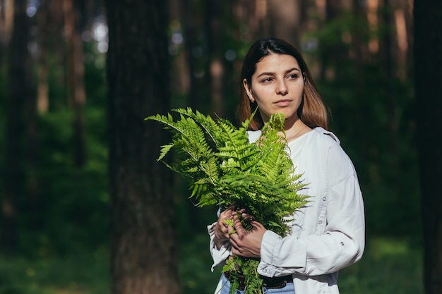 Een vrouw in het bos knuffelt een boeket varens, een jonge activist beschermt het bos