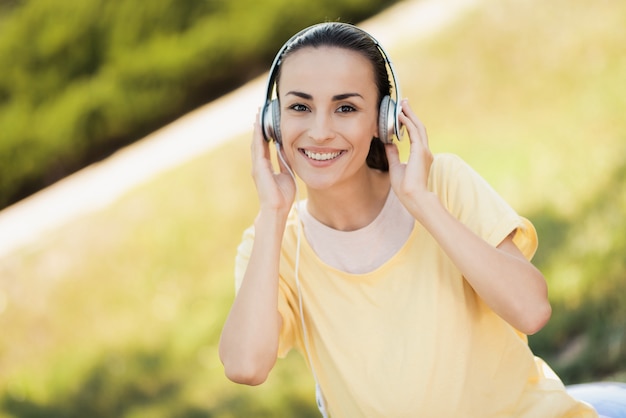 Een vrouw in het park luistert naar muziek op de koptelefoon.