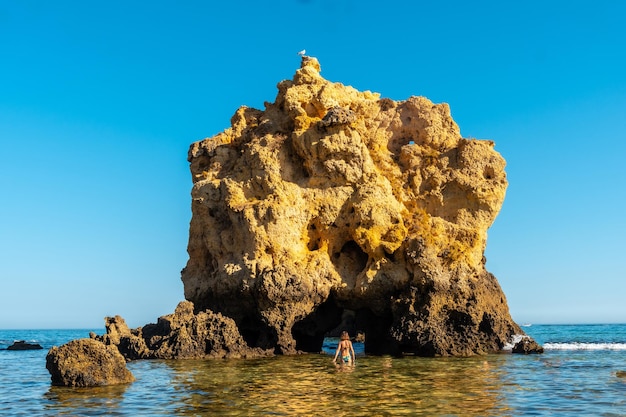 Een vrouw in het water naast de rotsen bij praia dos arrifes algarve strand albufeira portugal