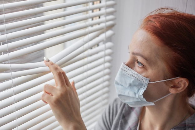 Een vrouw in quarantaine in zelfisolatie die een medisch masker draagt