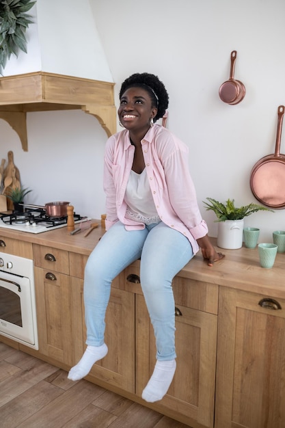 Een vrouw in roze shirt zittend op de tafel in de keuken