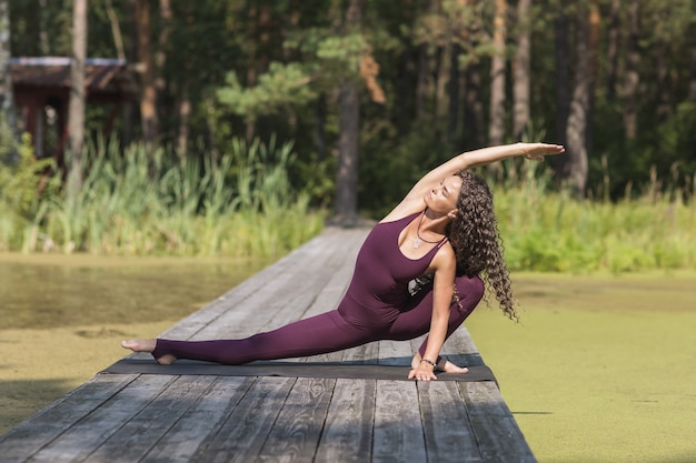 Een vrouw in sportkleding die yoga beoefent, doet de Skandasana- of surfer-lunge-oefening in het park