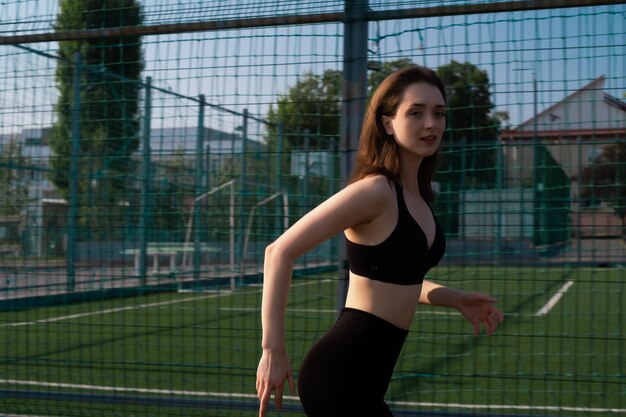 Een vrouw in sportkleding traint in een sportstadion. Een fitte vrouw die buiten joggt.