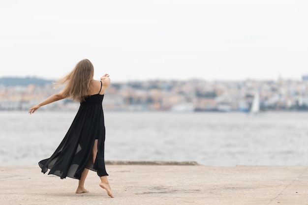 Een vrouw in zwarte jurk dansen op de pier uitzicht vanaf de achterkant