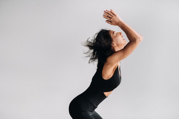 Een vrouw in zwarte sportkleding is bezig met dynamische kali-meditatie in de yogazaal