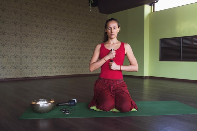 Een vrouw is bezig met meditatie met voorwerpen in haar handen en verschillende wierook zittend op een mat