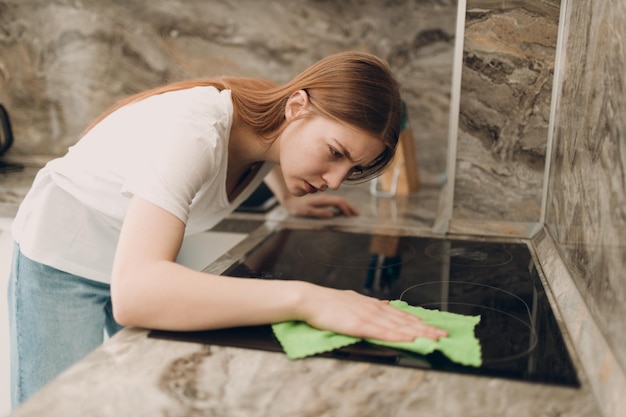 Een vrouw is in de keuken aan het schoonmaken met een doek in haar handen
