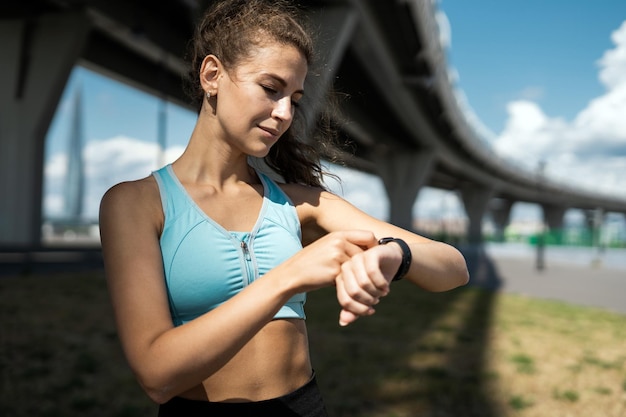 Een vrouw kijkt al wandelend op haar horloge.