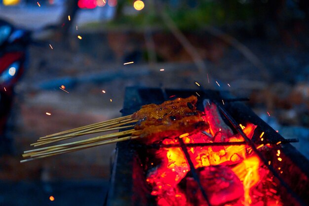 Een vrouw kookt saté kebabs, populair in Maleisië en Indonesië, op straat. Straatvoedsel in Maleisië.