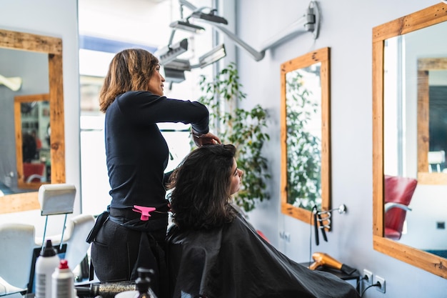 Een vrouw krijgt haar haar geknipt door een klant in een salon.