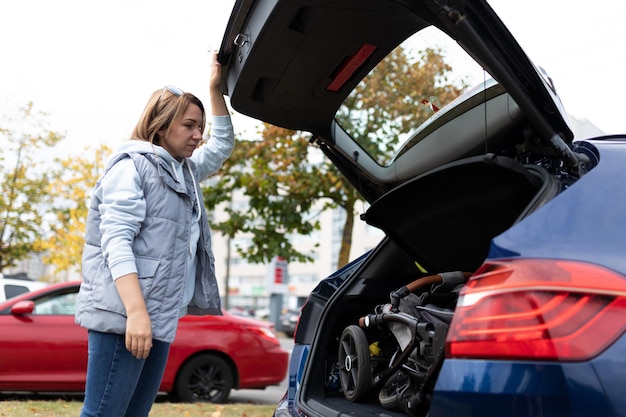 Foto een vrouw laadde een kinderwagen in de kofferbak van een auto