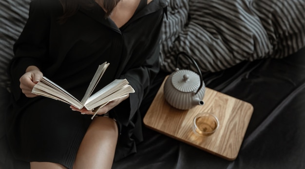 Een vrouw leest een boek terwijl ze in een comfortabel bed ligt.