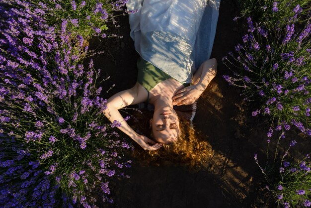 Een vrouw ligt in de zomer bij zonsopgang in een lavendelveld