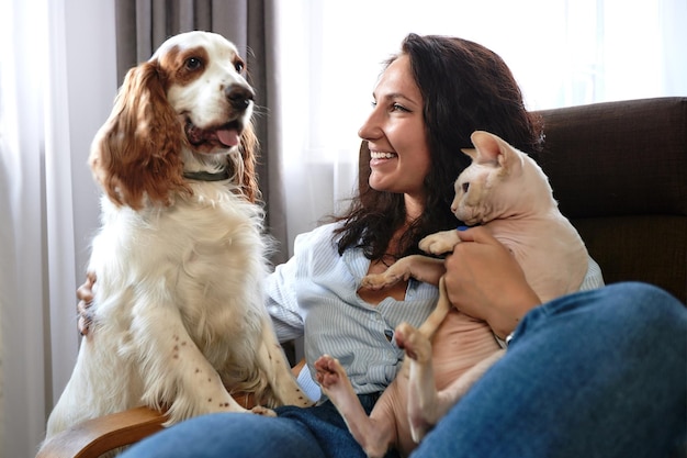 Een vrouw ligt op een bank met een kat en een hond love for pets concept