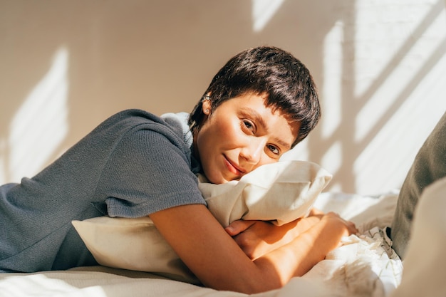 Een vrouw ligt op een bed in het heldere zonlicht van het raam.