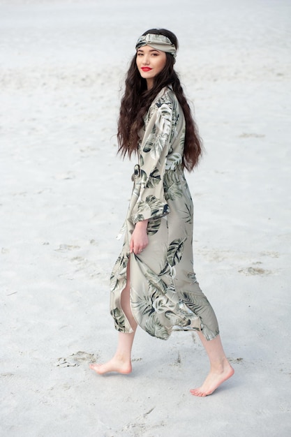 Een vrouw loopt op het strand in een jurk met de tekst palmbomen.