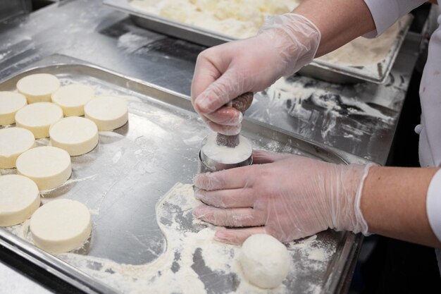 Een vrouw maakt cheesecakes met de hand in een fabriek voor de productie van voedsel