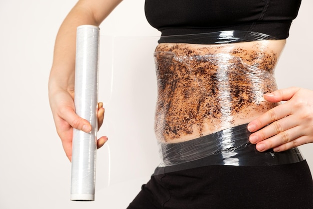 Een vrouw maakt een buikomslag met een koffie-anticellulitis bodyscrub