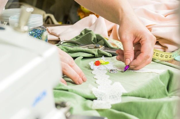 Een vrouw maakt sieraden een thuisworkshop Vrouwelijke handen die een accessoire maken met kralen en linten Schoonheid creativiteit het concept van handwerk