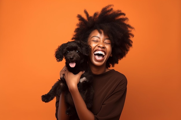 Een vrouw met afrohaar houdt een hond vast en glimlacht op een oranje achtergrond