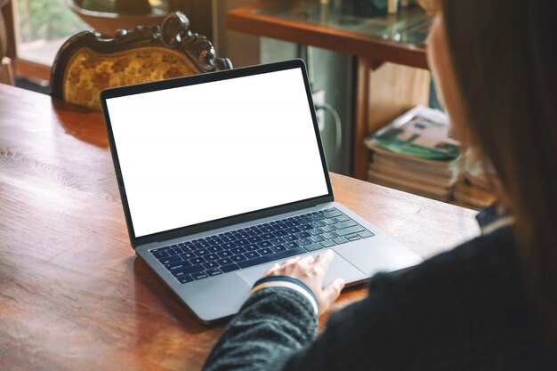 een vrouw met behulp van en aanraken op laptop touchpad met lege witte desktop scherm op houten tafel