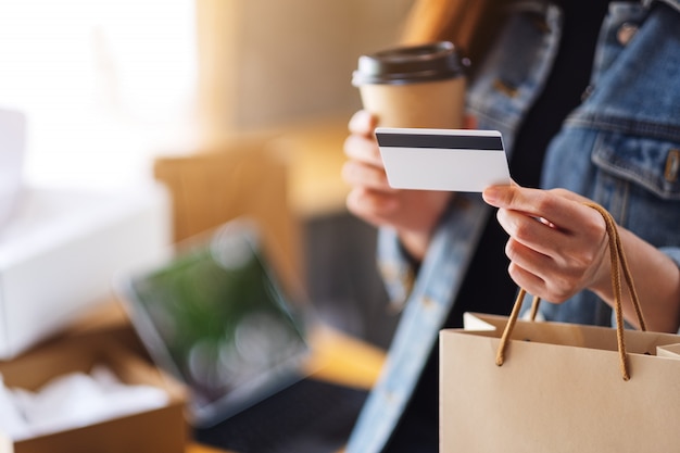 Een vrouw met boodschappentassen, creditcard en koffiekopje voor online winkelen concept