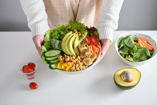 Een vrouw met een bord heerlijke en gezonde salade met gegrilde tofu close-up afbeelding