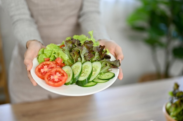 Een vrouw met een bord verse en biologische groentesalade in haar eetkamer