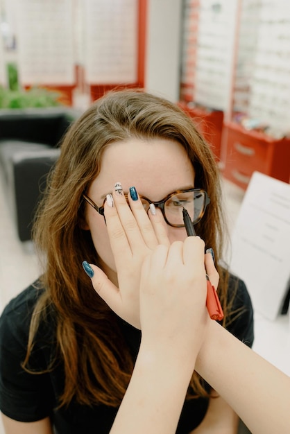 Een vrouw met een bril bedekt haar oogarts met een rode doos achter haar