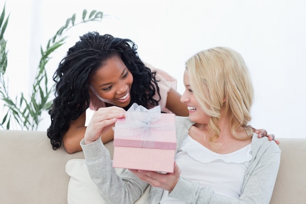 Een vrouw met een cadeau lacht naar haar vriend