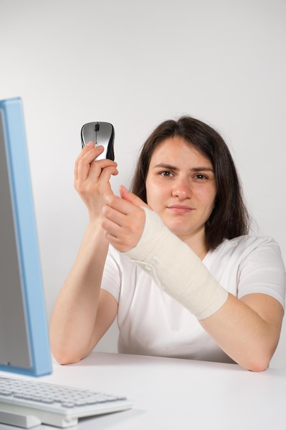 Een vrouw met een elastisch verband om haar pols zit voor een computer