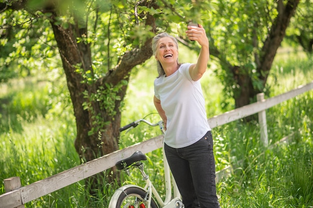 Een vrouw met een fiets die selfie maakt en lacht