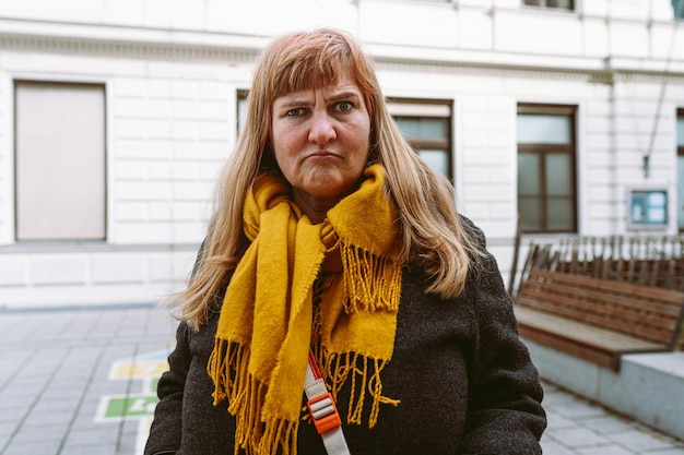 Een vrouw met een gele sjaal staat voor een gebouw met een wit gebouw achter haar.