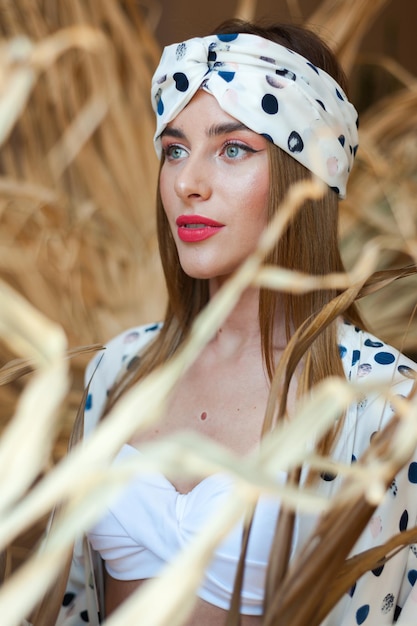 Een vrouw met een gestippelde hoofddoek staat in een tarweveld.