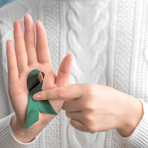 Foto een vrouw met een groen lint met groene lint in haar handen gezondheidszorg en wereldkankerdagconcept