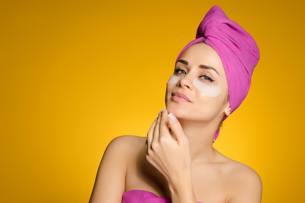 Een vrouw met een handdoek op haar hoofd plakte pleisters onder haar ogen