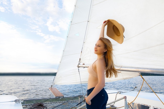 Foto een vrouw met een hoed op een jacht, tegen de lucht en de zee.