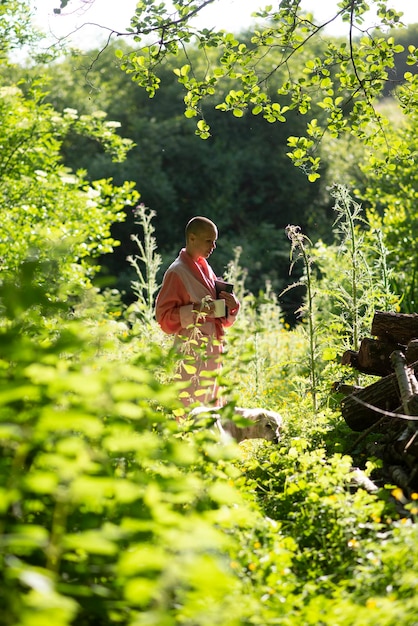 Een vrouw met een kaalgeschoren hoofd in een roze gewaad in het bos