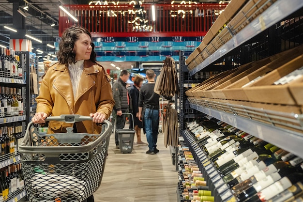 Een vrouw met een karretje doet aankopen in een supermarkt